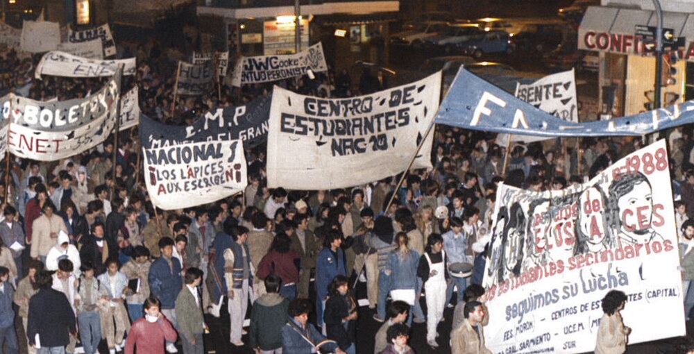 Multitud de estudiantes reunidos durante una movilización nocturna con banderas y carteles en defensa de sus derechos