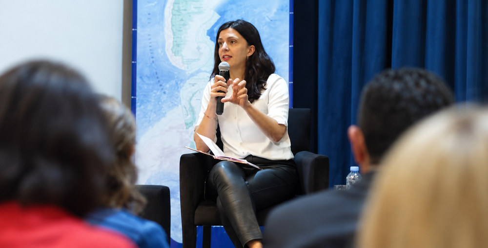Laura De Marinis habla con un micrófono durante una exposición ante el público.
